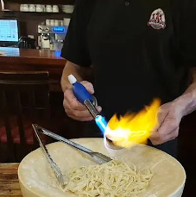 Massa finalizada na roda de queijo flambada