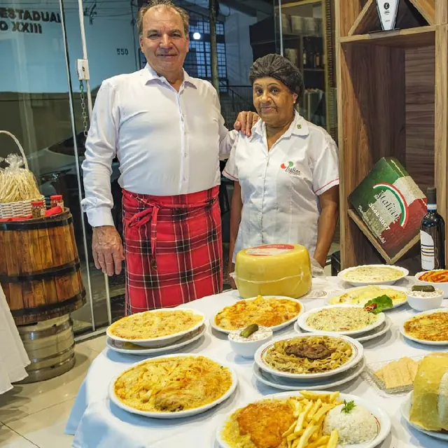 Proprietário e cozinheira com mesa de massas e grelhados da Italian em Americana